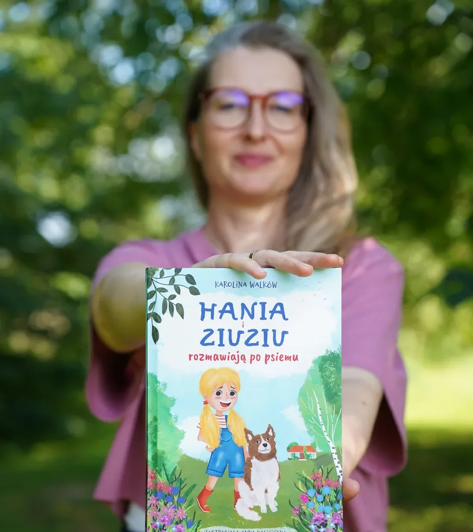 Karolina Walków trzyma książkę Hania i Ziuziu rozmawiają po psiemu